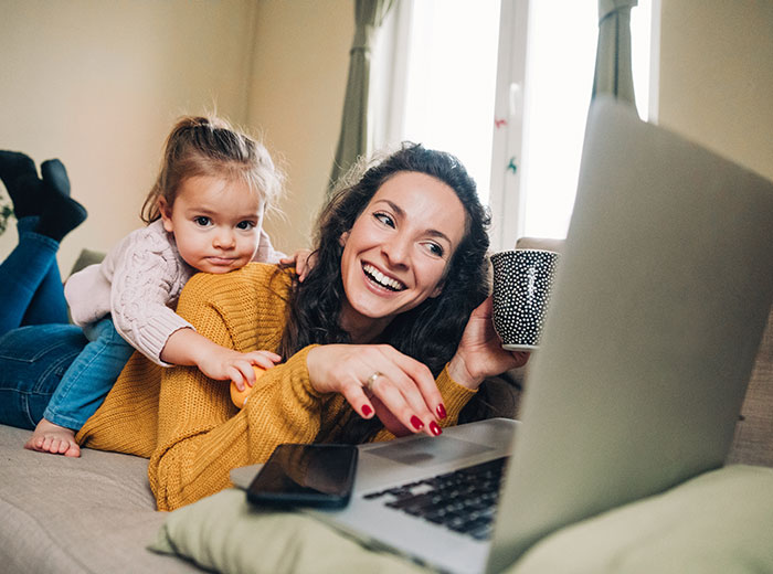 A woman and her daughter happily looking at a laptop screen